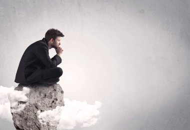 Ofis çalışanı kayanın tepesinde oturuyor.