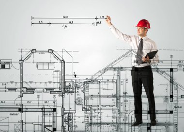 Genç bir mimar ev planı çiziyor.
