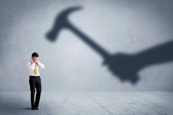 Business person afraid of a shadow hand holding hammer concept — Stock Photo, Image