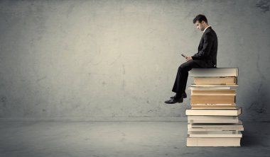 Adam kitaplar üzerinde oturan dizüstü bilgisayar ile