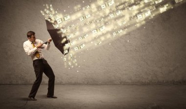 İş adamı dolar yağmuruna karşı şemsiye tutuyor