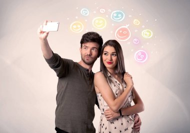 Mutlu çift gülen yüzle selfie çekiyor.