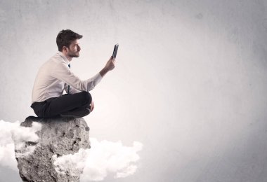 Ofis çalışanı kayanın tepesinde oturuyor.