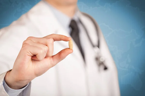 Doutor em branco segurando uma pílula — Fotografia de Stock