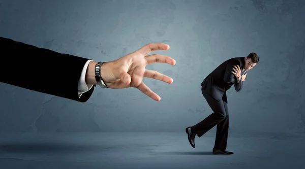 Hombre de negocios huyendo de un concepto de mano enorme —  Fotos de Stock