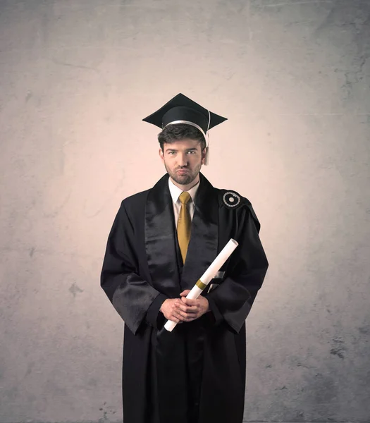 Retrato de un joven estudiante graduado con antecedentes gruñones —  Fotos de Stock