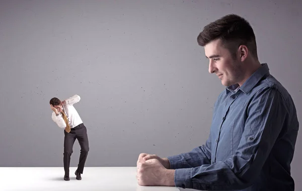 Young businessman fighting with miniature businessman — Stock Photo, Image