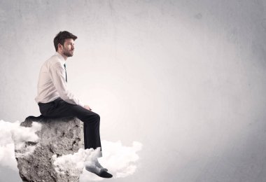 Ofis çalışanı kayanın tepesinde oturuyor.