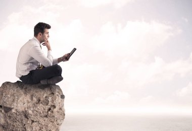 İş adamı taşın üstünde oturuyor.