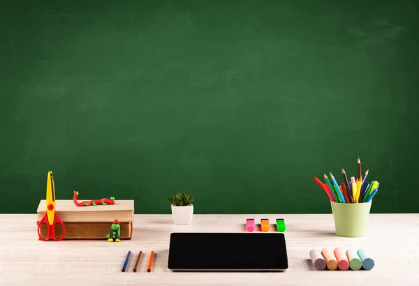 Schoolspullen op bureau met leeg schoolbord — Stockfoto