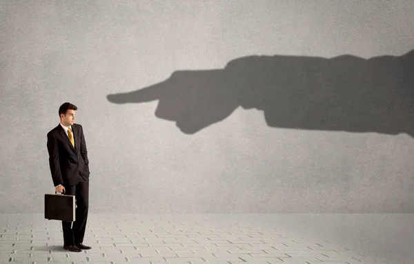Business person looking at huge shadow hand pointing at him conc — Stock Photo, Image