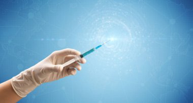 Kadın doktor elinde şırınga tutuyor.