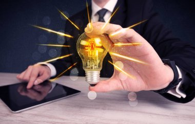 bir elektrik ampulü tutan iş kişi