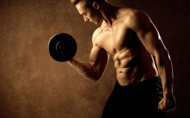 Kas formundaki vücut geliştirici sporcu ağırlık kaldırıyor 