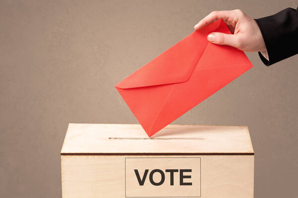 Крупный план мужской руки, помещающей голоса в урну для голосования
