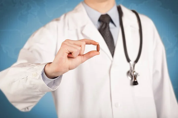 Доктор в белом держит таблетку — стоковое фото