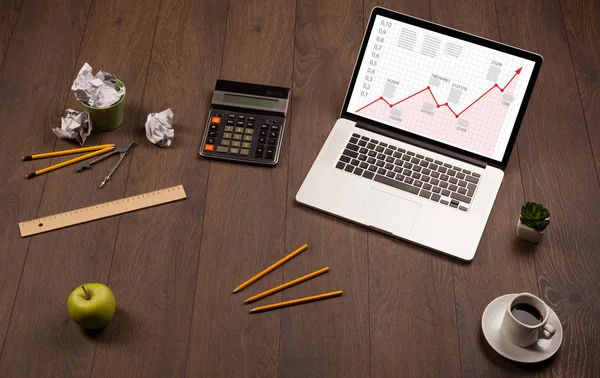 Computerschreibtisch mit Laptop und rotem Pfeildiagramm auf dem Bildschirm — Stockfoto