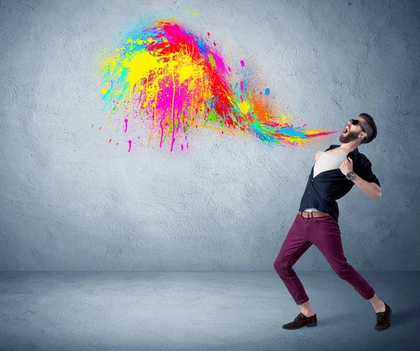 Hipster guy shouting colorful paint on wall — Stock Photo, Image