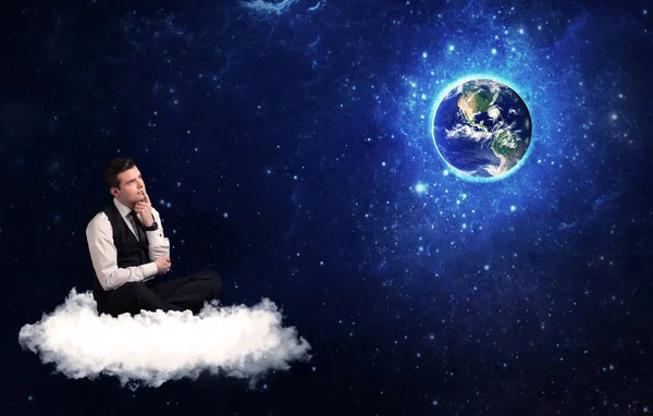 Człowiek siedzi na chmurze patrząc na planecie Ziemia — Zdjęcie stockowe