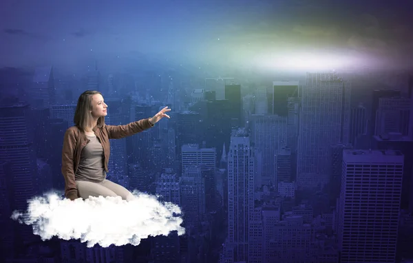 Kobieta siedzi na chmury nad miastem — Zdjęcie stockowe