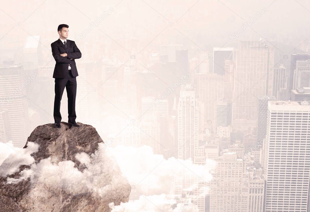 Happy businessman standing on stone top