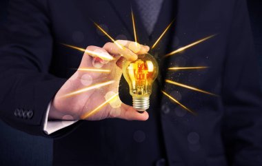 bir elektrik ampulü tutan iş kişi