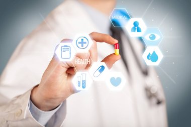 Beyazlı bir doktor elinde hap tutuyor.