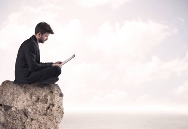 İş adamı taşın üstünde oturuyor.