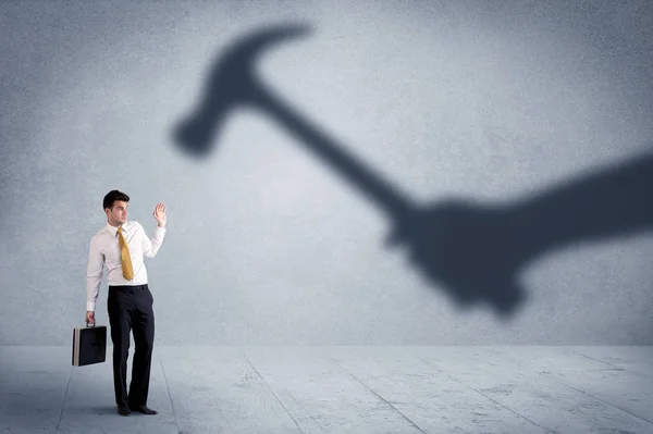 Business person afraid of a shadow hand holding hammer concept — Stock Photo, Image