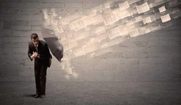 Business man protecting with umbrella against wind of papers — Stock Photo, Image