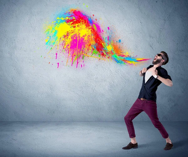 Hipster guy shouting colorful paint on wall — Stock Photo, Image