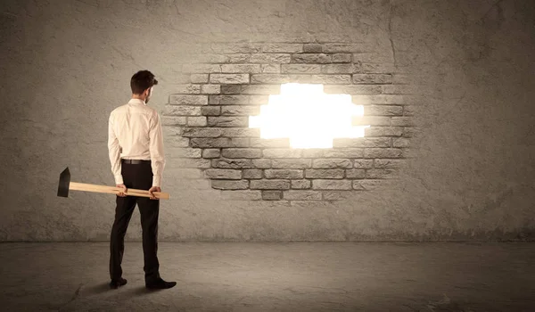 Business man hitting brick wall with hammer and opening a hole — Stock Photo, Image