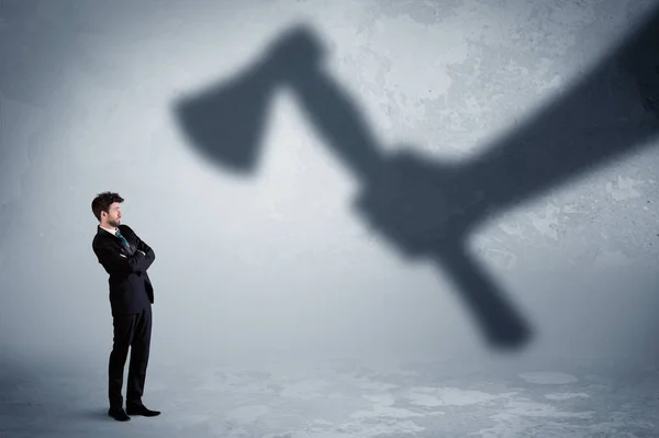 Empresario temeroso de una enorme mano sombra sosteniendo un concepto de hacha — Foto de Stock