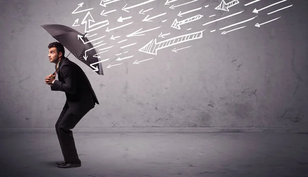 Business man standing with umbrella and drawn arrows hitting him — Stock Photo, Image