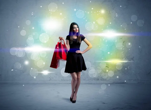 Alışveriş torbaları ve parıltılı ışıklarla alışveriş merkezindeki kadın. — Stok fotoğraf