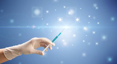 Kadın doktor elinde şırınga tutuyor.