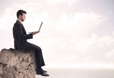 İş adamı taşın üstünde oturuyor.