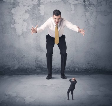 Büyük işletme zorbası küçük iş arkadaşına bakıyor.
