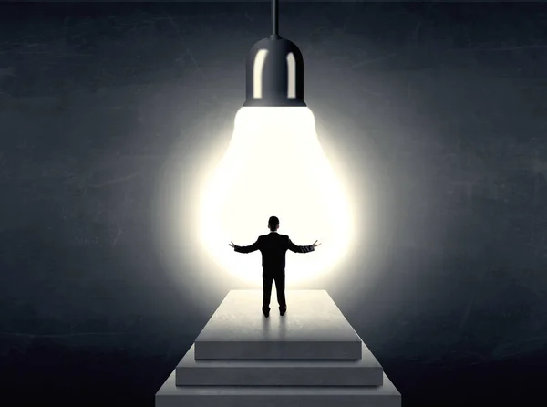 Man standing on a step in front of a huge light bulb — Stock Photo, Image