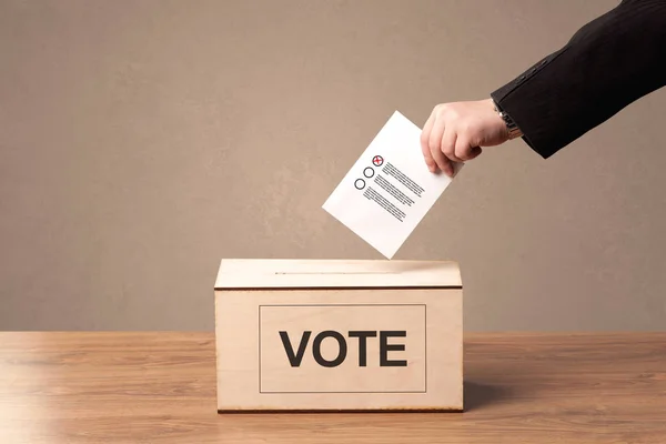 Fechar a mão masculina colocando voto em uma urna — Fotografia de Stock