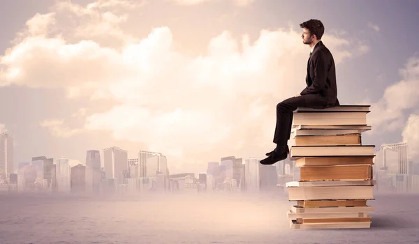 Homme assis sur une pile de livres au-dessus de la ville — Photo