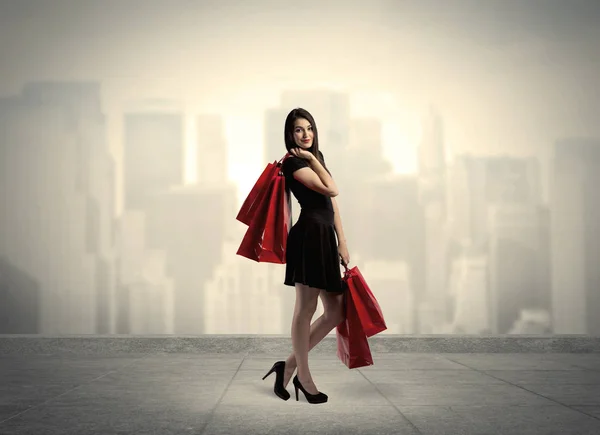 Κομψό κορίτσι της πόλης με κόκκινες τσάντες για ψώνια — Φωτογραφία Αρχείου