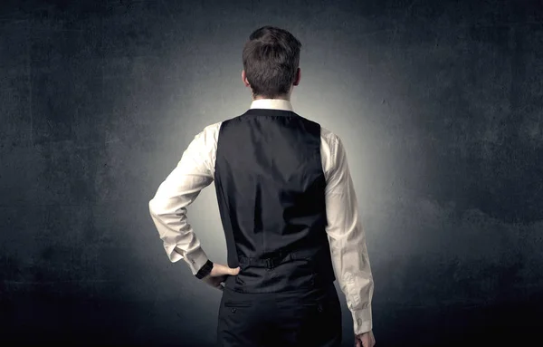 Бизнесмен, стоящий впереди на черной стене — стоковое фото