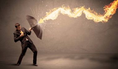 İş adamı kendini bir umbrell ile bir yangın oka savunmak