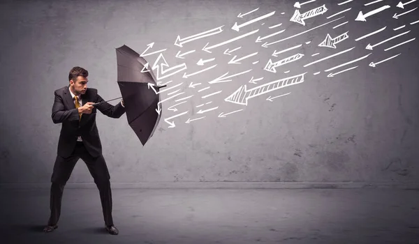 Homem de negócios de pé com guarda-chuva e flechas desenhadas batendo nele — Fotografia de Stock