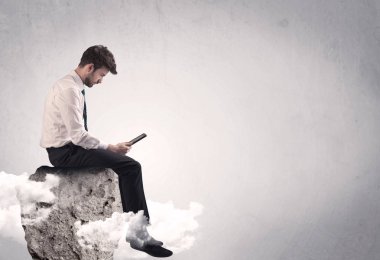 Ofis çalışanı kayanın tepesinde oturuyor.