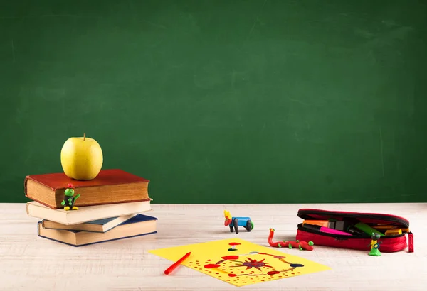 Schoolspullen op bureau met leeg schoolbord — Stockfoto