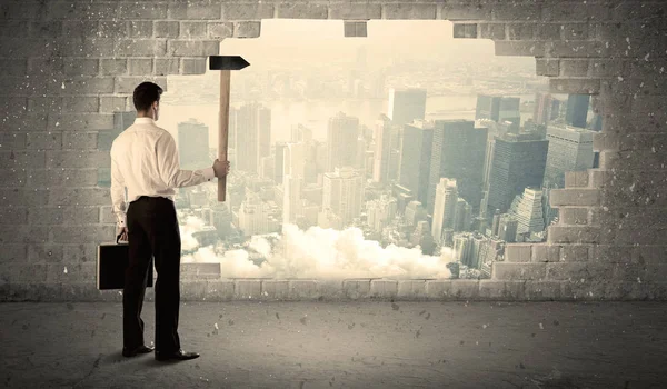 街の眺めでハンマーで壁にぶつかるビジネスマン — ストック写真