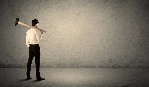 Uomo d'affari in piedi di fronte a un muro scontroso con un martello — Foto Stock