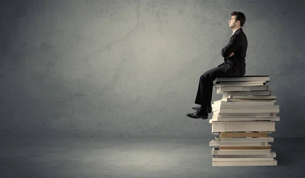 Homme élégant assis sur des livres — Photo